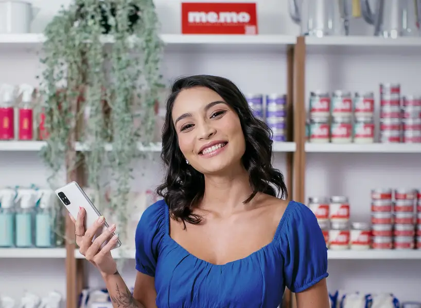 Yasmin, CEO da Me.Mo segurando celular com sua loja online